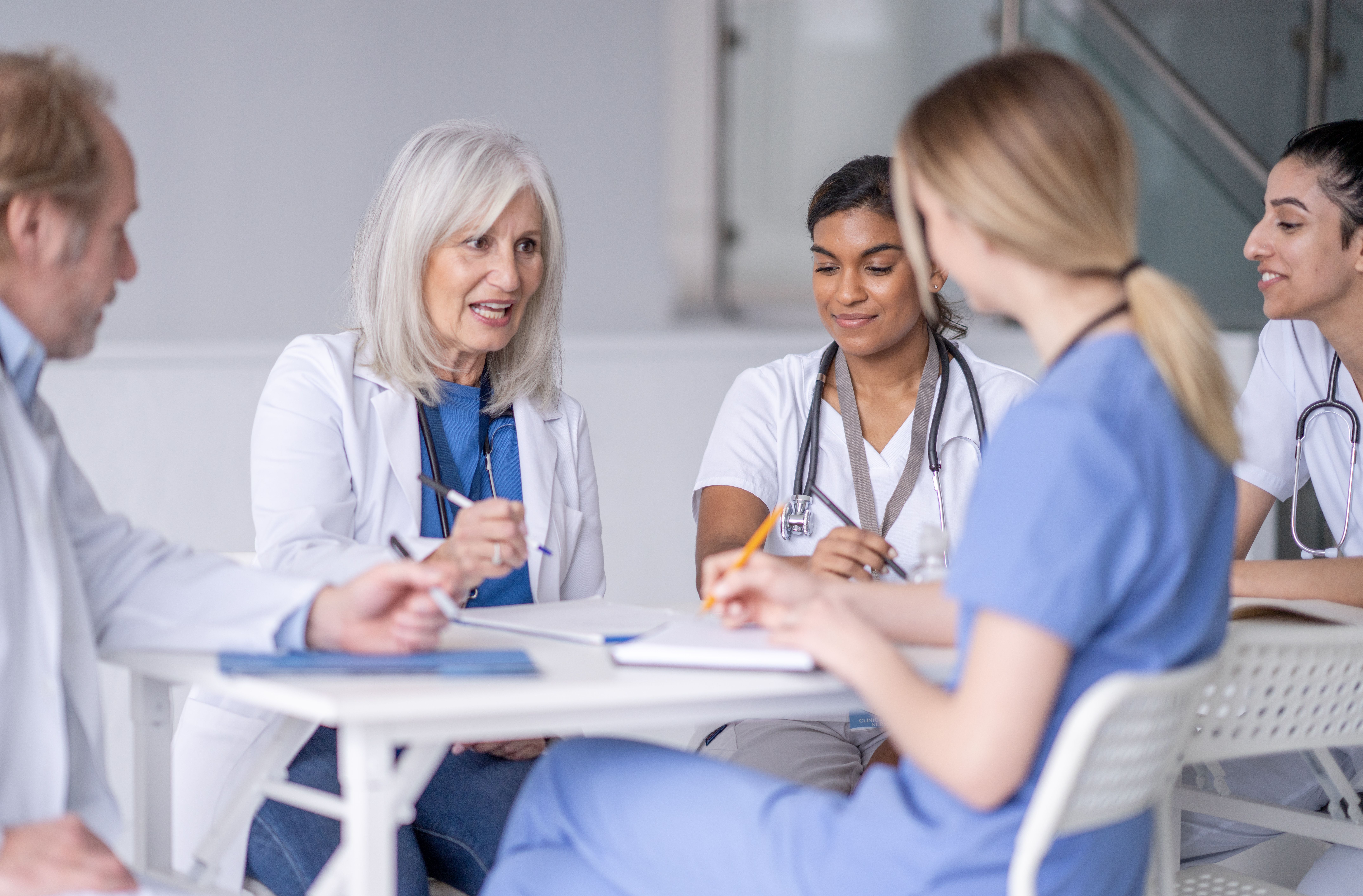 Fröhliche Pflegefachfrau mit Kopftuch und Stethoskop, blickt direkt in die Kamera